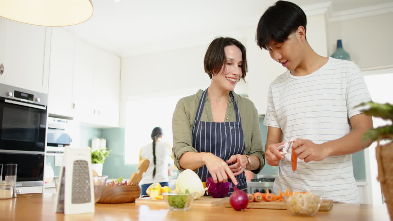 Cooking together, mother and son preparing vegetables in modern kitchen