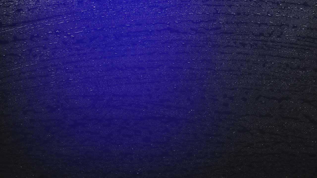 Raindrops reflecting flashing police lights at night. Raindrops on a wet surface reflect pulsating red and blue police lights at night. For crime, emergency, or urban drama concepts