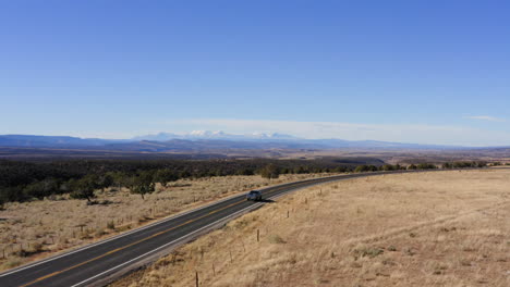 Aerial-view-of-two-cars-driving-down-country-road-in-Norwood,-Colorado