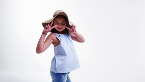 girl wearing hat walks posing against white studio background