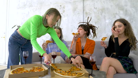 happy four female friends eating pizza and talking at home