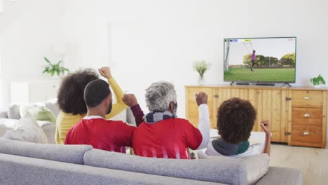 video of african american family sitting on sofa and watching football at home