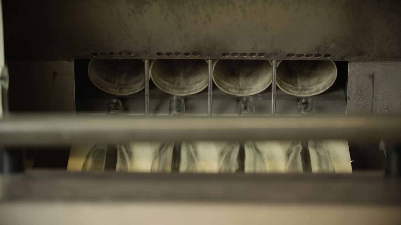 Empty glass bottles are labelled in a wine production facility