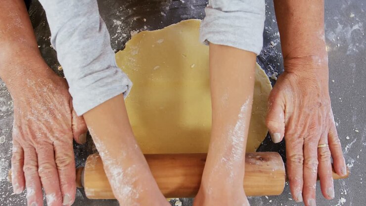 Grandmother and little girl hands flattening dough with rolling pin 4K 4k