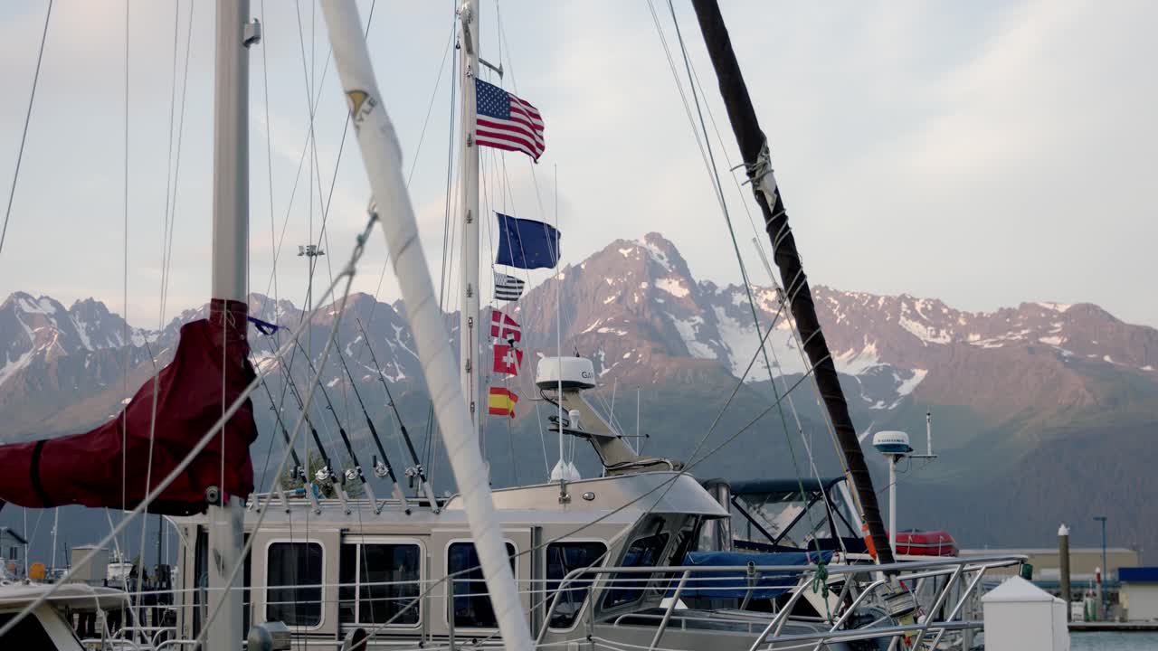 banderas multinacionales en barcos de vela y pesca ondeando con viento fuerte en el puerto de seward, alaska, ee.uu., amplia vista estática