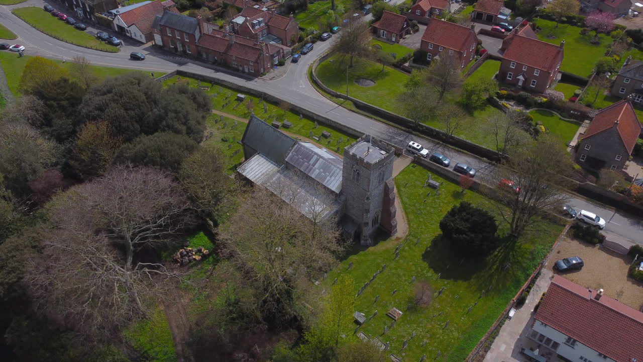 drone aéreo de alta rotación disparó alrededor de la antigua iglesia en un hermoso pueblo con casas y árboles en un día soleado en el mercado de burnham north norfolk reino unido