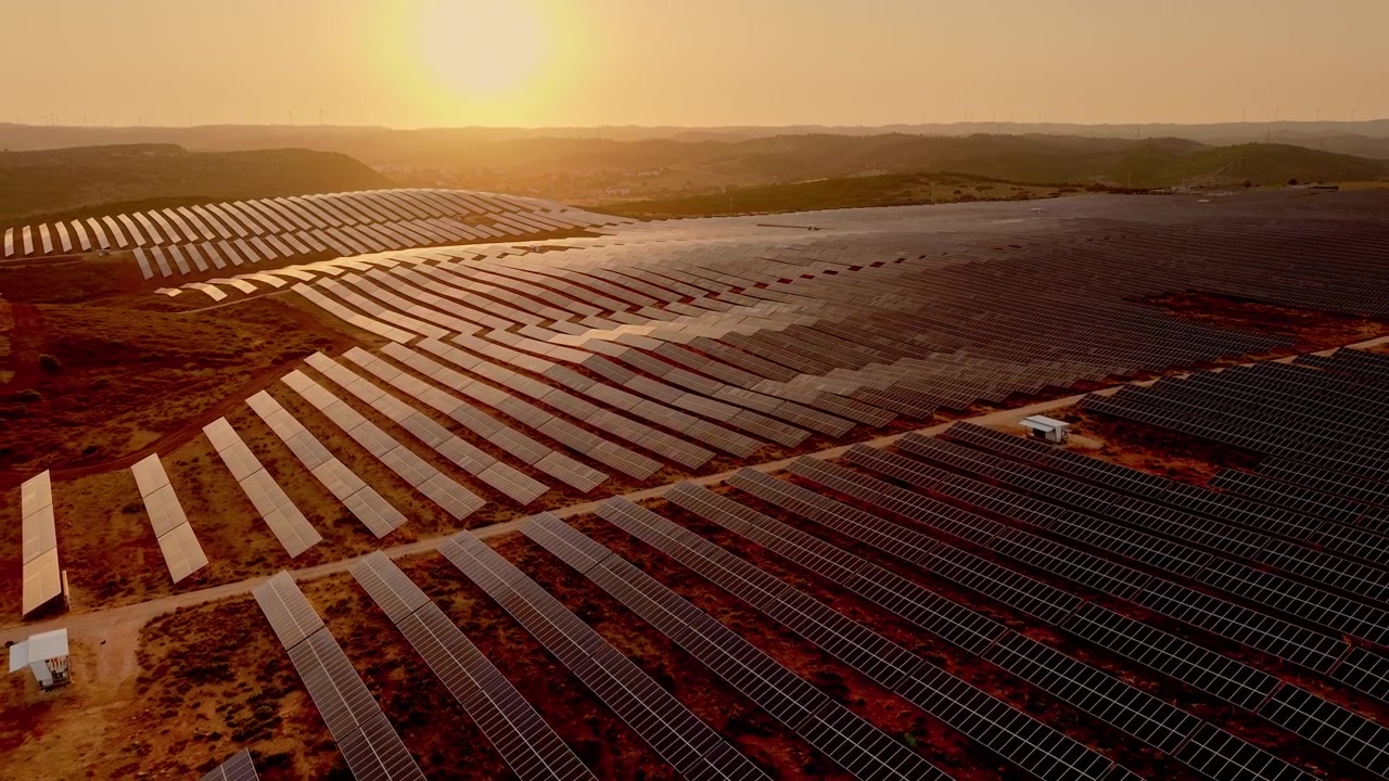 Luftfoto af stor solcellepark ved solnedgang