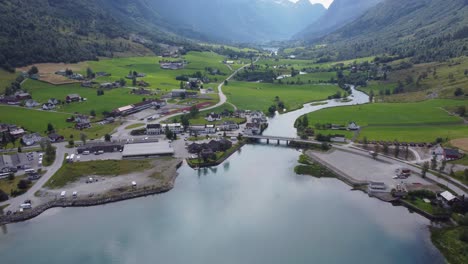Olden-town-centre-with-misty-Oldedalen-valley-in-background---Reverse-aerial-showing-Olden-and-fjord-overview-during-summer-day---Norway
