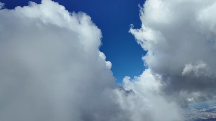 POV flying though a blue sky with some white stormy clouds