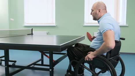 a man in a wheelchair plays ping pong. people with disabilities play table tennis. rehabilitation of the disabled. paralympic sport.