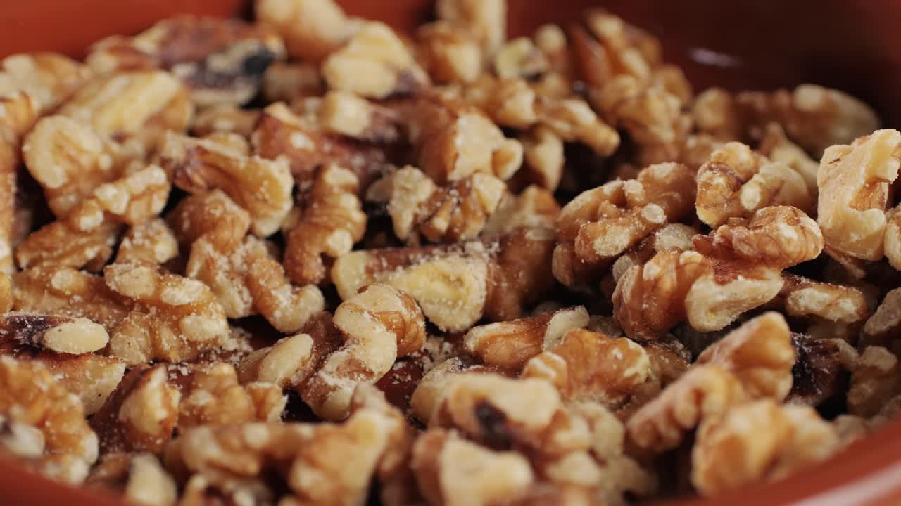 Walnuts without shell close-up macro. Man hand take a piece of walnut. Peeled nuts. Healthy snacks. Product rich in minerals and vitamins.