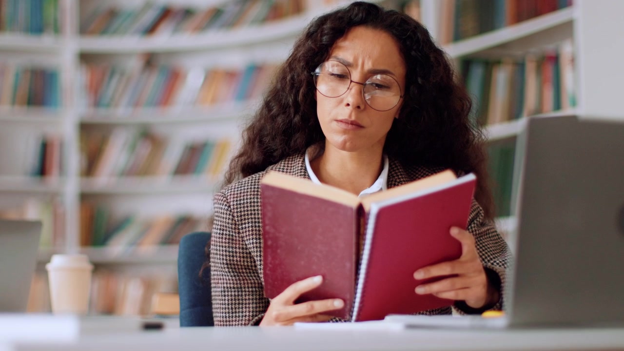 Mulher Concentrada Lendo um Livro em uma Biblioteca
