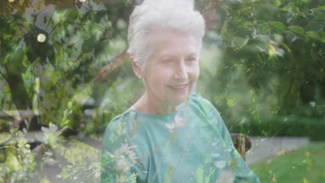 composite video of f hanging leaves against caucasian senior woman smiling in the garden