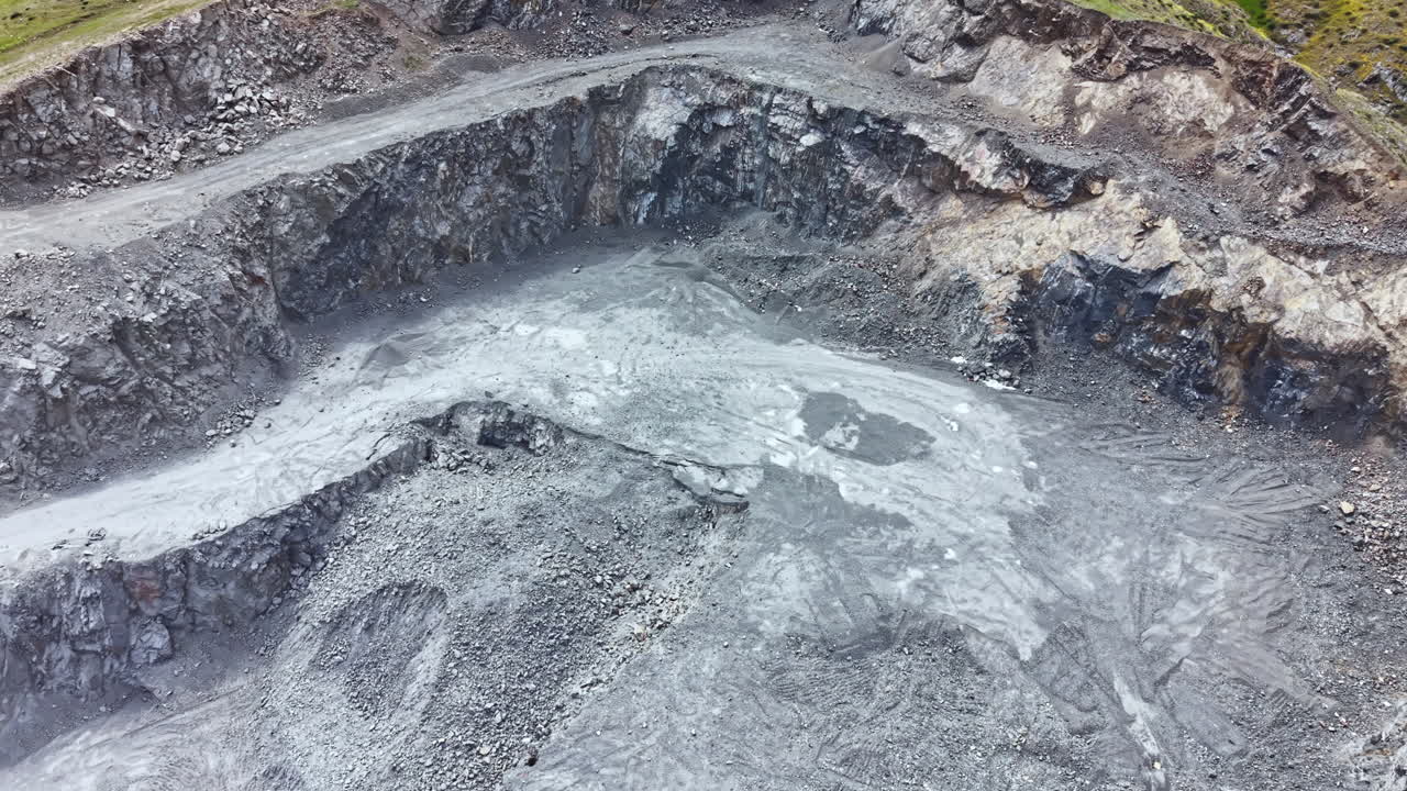 Excavation process in a rock quarry during daylight hours with heavy machinery actively breaking down stone material