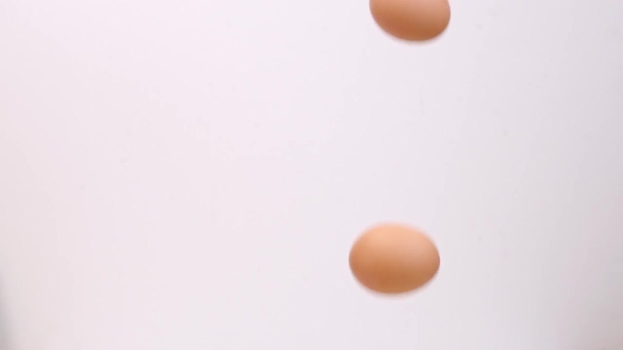 Brown eggs falling on white backdrop in slow motion