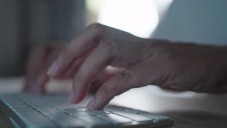 close up hands working overtime typing research laptop office desk at night