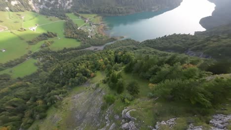 Volando-Cerca-Del-Pico-Escarpado-Y-Del-Follaje-Verde-Del-Bosque,-Llegue-Al-Pintoresco-Lago