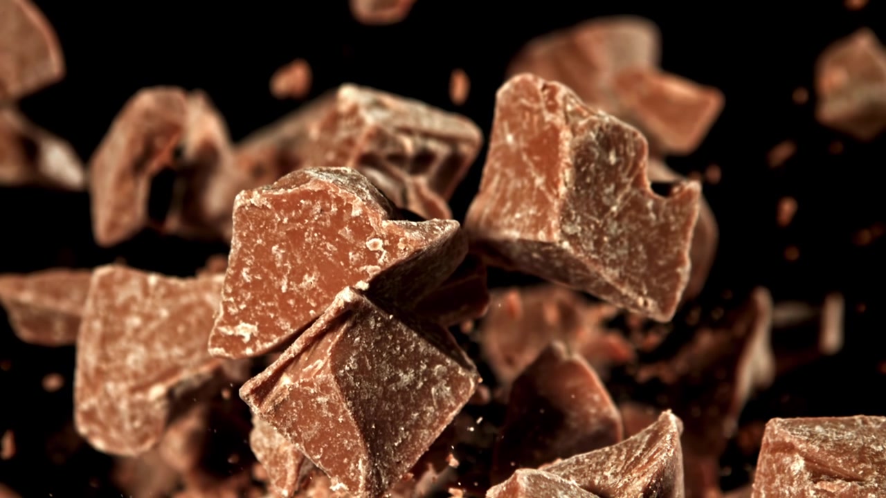 Pezzi di cioccolato che cadono al rallentatore su sfondo nero
