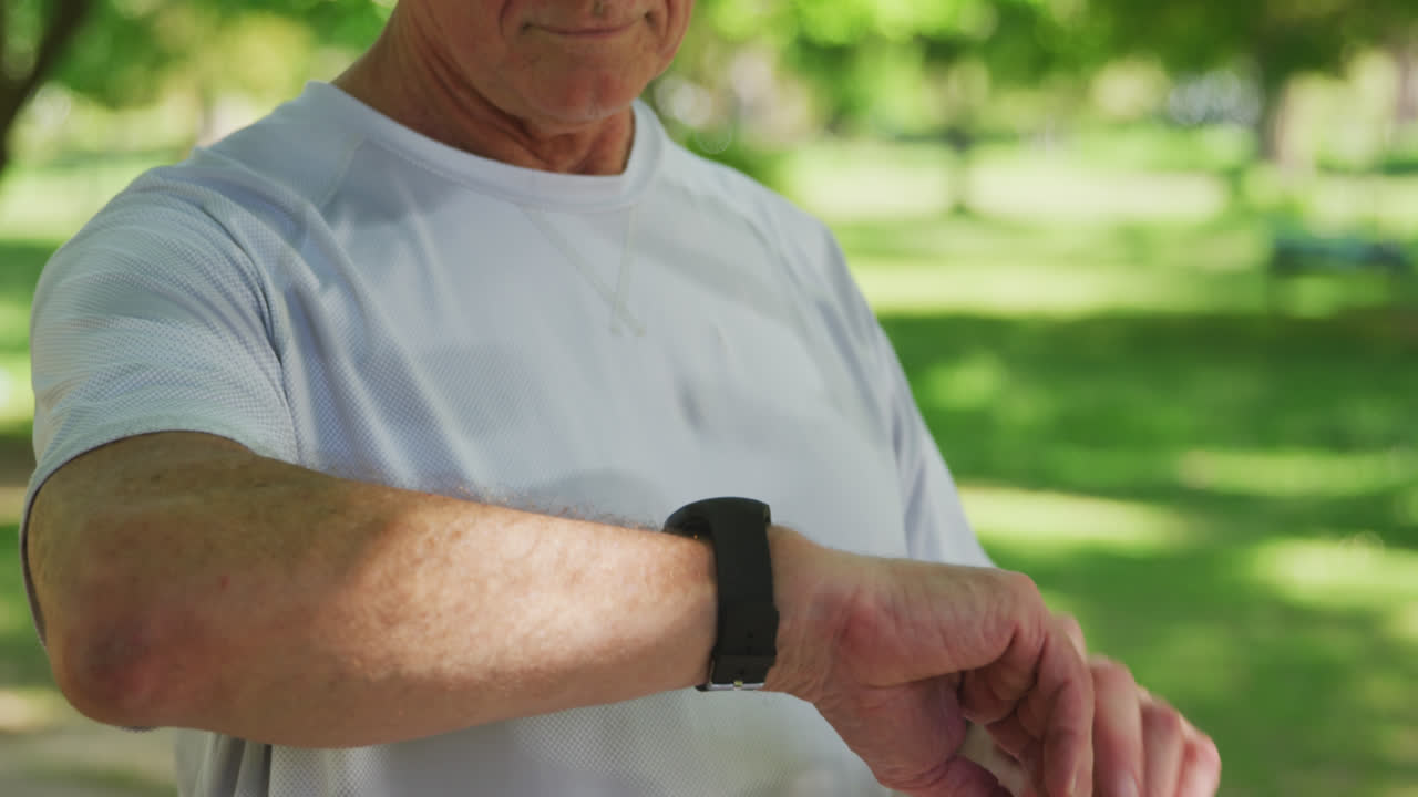 Uomo anziano che corre nel parco usando uno smartwatch