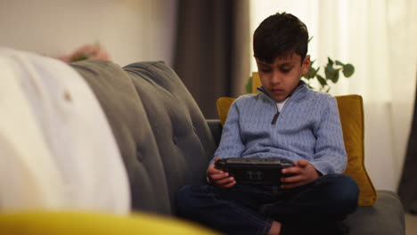 Young-Boy-Sitting-On-Sofa-At-Home-Playing-Game-Or-Streaming-Onto-Handheld-Gaming-Device-5