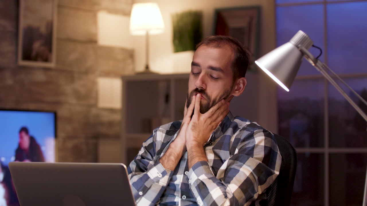 Man stretching and feeling tired in front of laptop