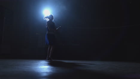 Training-girl-fighter-jumping-rope-in-a-dark-room