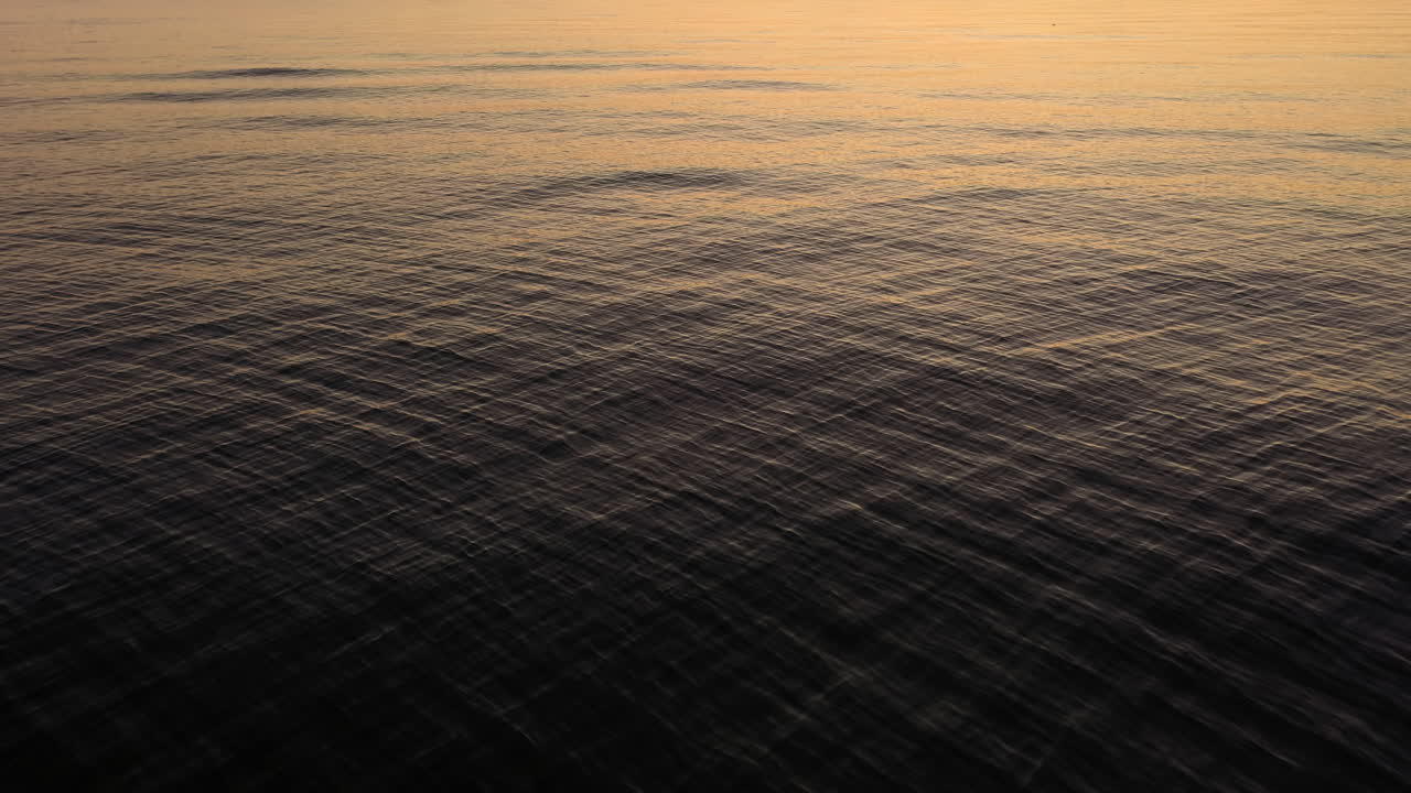 Calm Ocean Ripples With Reflection Of Sunset Light On The Surface