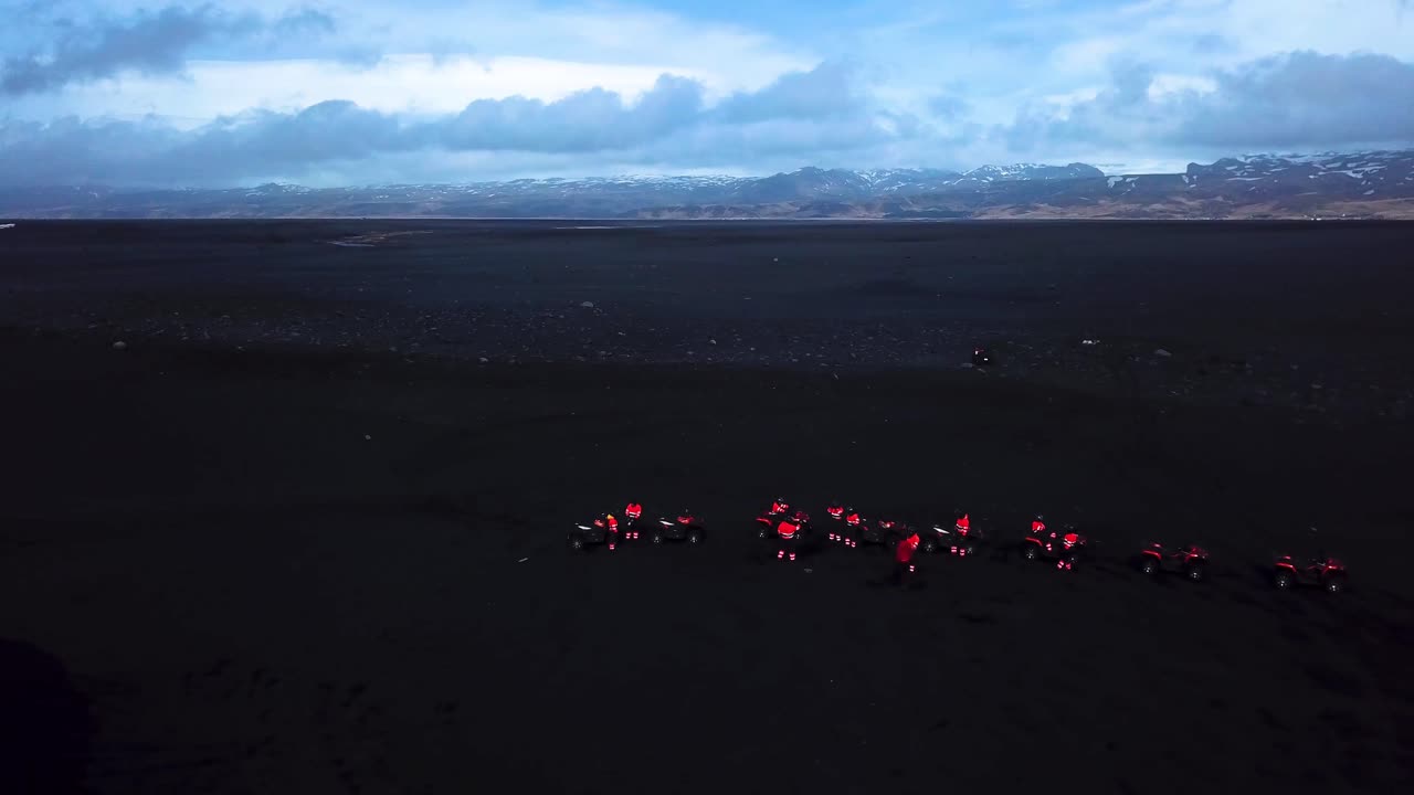 Aerial landscape view of red quad bikes on Iceland black sand beach, next to the ocean