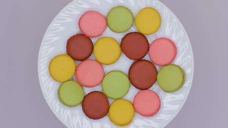 sweet color macaroons are rotating on white plate. top view.