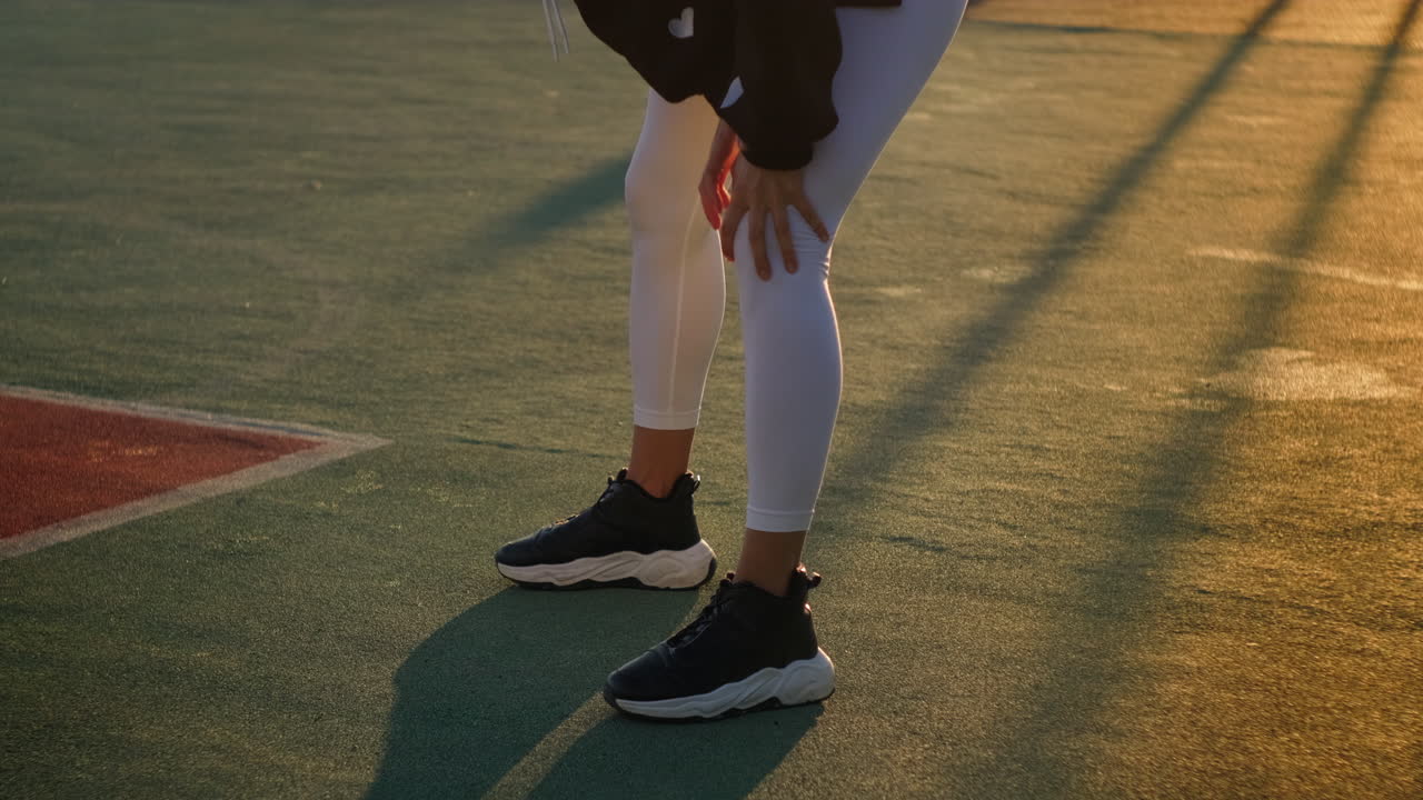 mujer estirándose en una cancha deportiva
