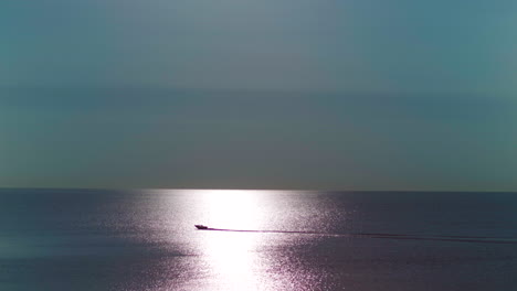 A-boat-moving-on-the-water-going-through-sunlight-during-sunrise