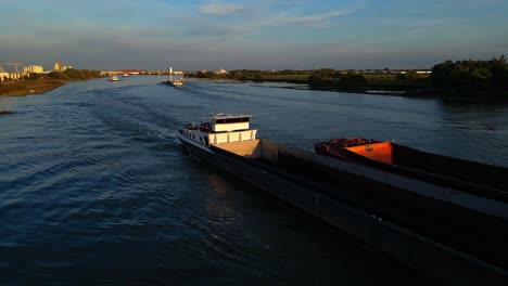 Aerial-View-of-Nautical-Traffic,-Cargo-Tank-Barge-Inland-Waterway-Vessel-Navigating-Along-River-Canal-in-Zwijndrecht-Netherlands-at-Sunset,-Coastline-Navigation-Along-Waterway