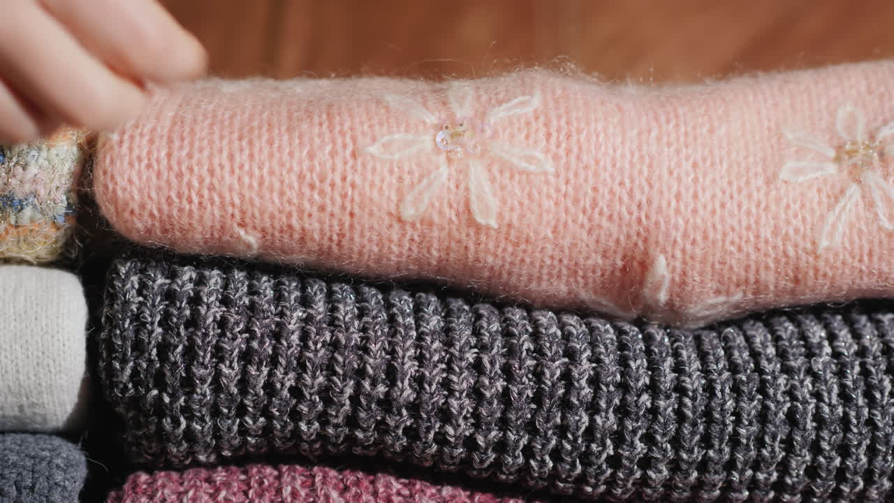 여자는 니트 따뜻한 옷을 더미에 넣습니다.