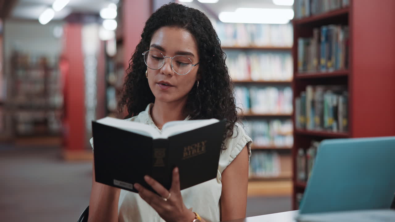 Junge Frau liest Heilige Bibel in einer Bibliothek