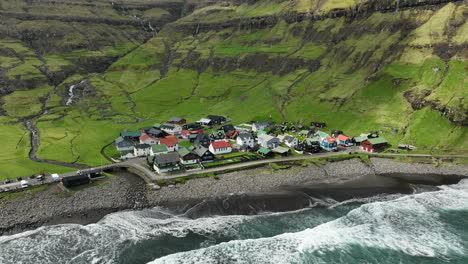 tjørnuvík village, faroe islands: aerial view traveling in towards the pretty village, with the ocean and mountains in the background