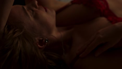 close up of a beautiful woman in a dark room sensually playing with her hair in slow motion