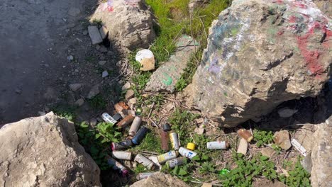 empty soda cans dumped on the ground between rocks in sunken city in san pedro, california