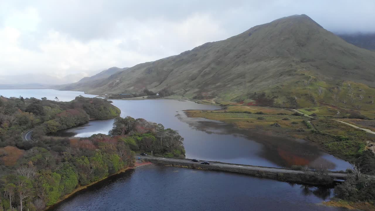 aerial del hermoso paisaje montañoso irlandés con vista al lago y coches en el puente