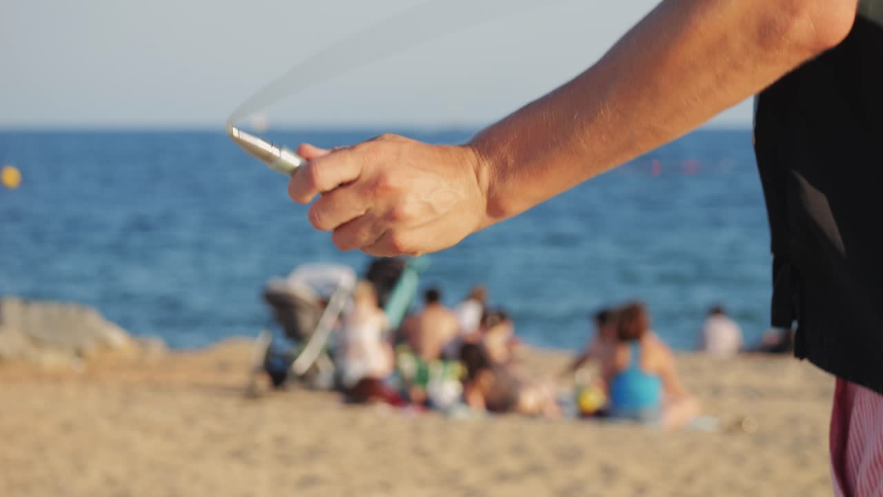 Person at the beach using a jumping rope and spray