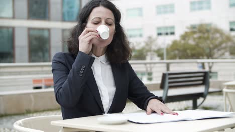 Businesswoman-reading-papers-and-drinking-coffee