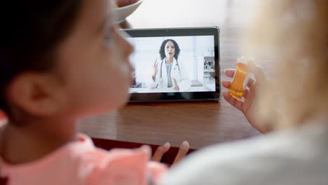 biracial female doctor having tablet video call with mother and sick daughter at home, slow motion