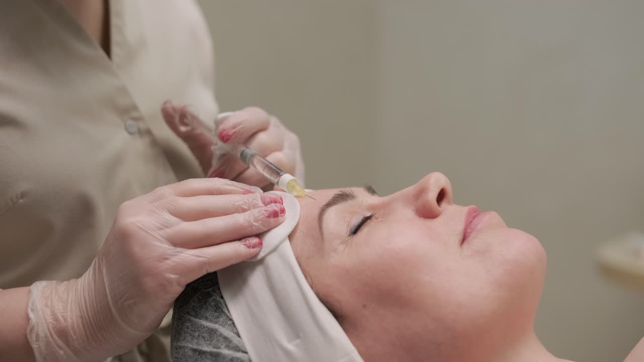 mujer haciendo terapia de botulino en una clínica de cosmetología moderna de cerca. cosmetólogo profesional haciendo inyección con toxina botulínica para rejuvenecer la piel de la cara.