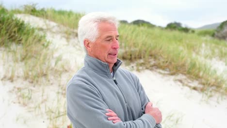 retired man standing on the beach shivering