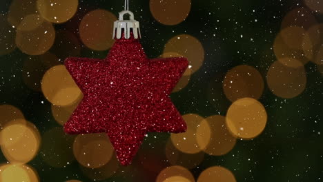 animation of snow falling over red star christmas bauble decoration