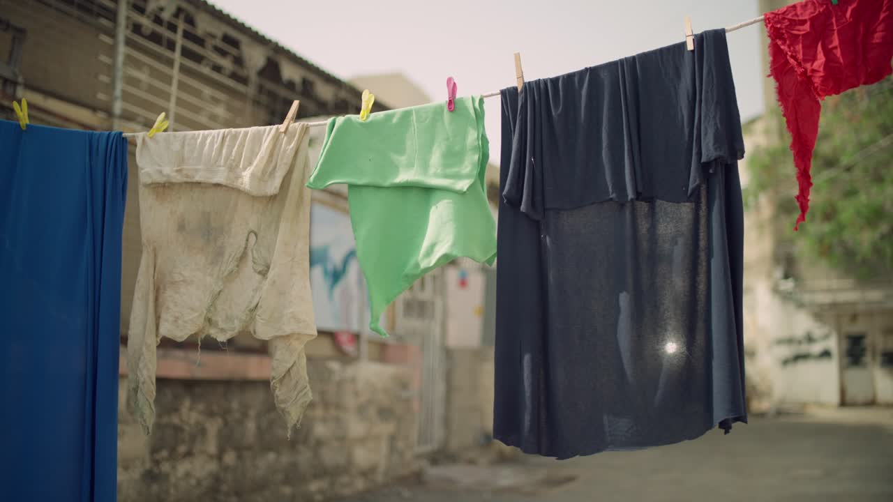 Dirty clothes and wear items hanging outdoors in street in slums or poor neighborhood in low income project housing. Sad and neglected atmosphere. Poor living conditions in shack in town or village