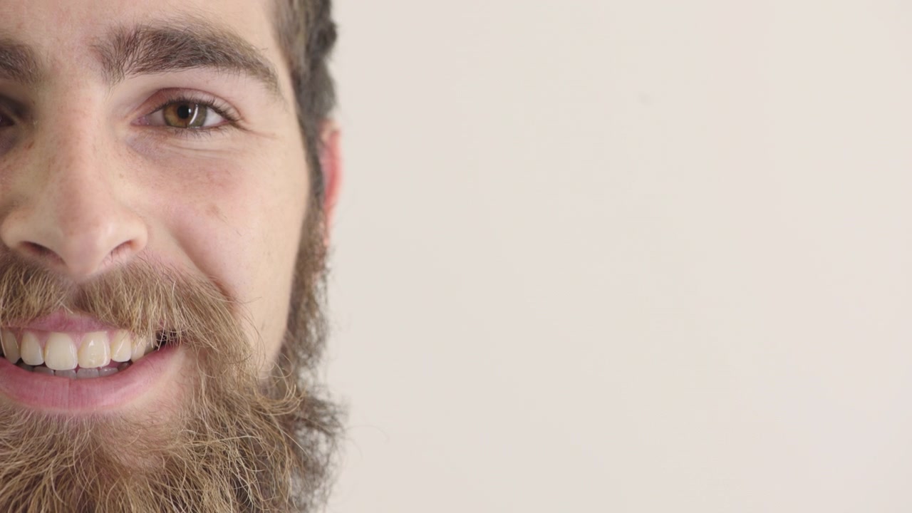 Primo piano di un giovane uomo con la barba che sorride