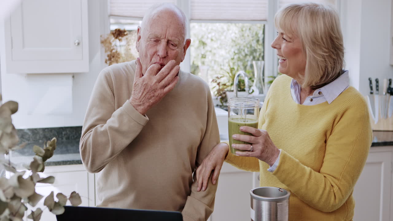Senior couple making smoothie together in their kitchen