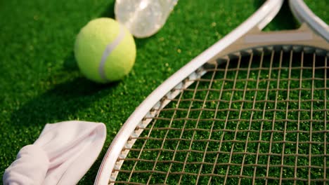 tennis ball, racket, water bottle and hair band in tennis court 4k