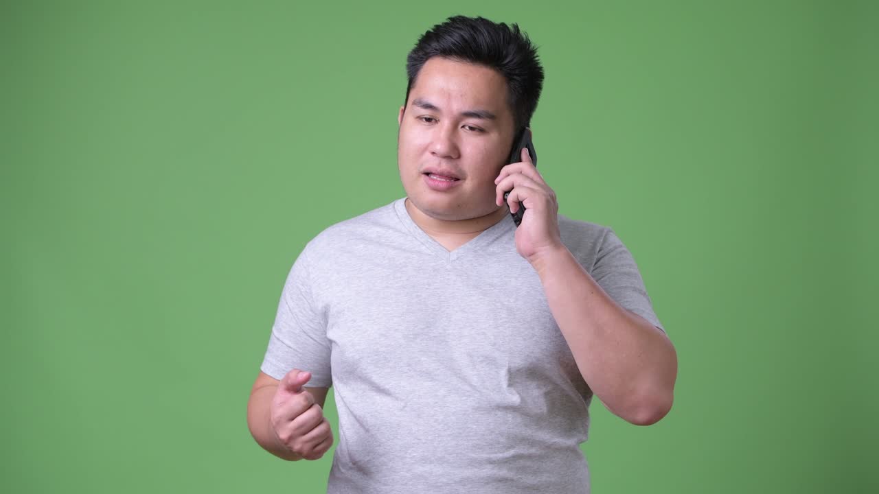 초록색 배경에 젊은 잘생긴 과체중 아시아인