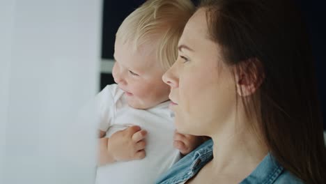 Nahaufnahmevideo-Von-Mutter-Und-Kleinkind,-Die-Durch-Das-Fenster-Schauen.